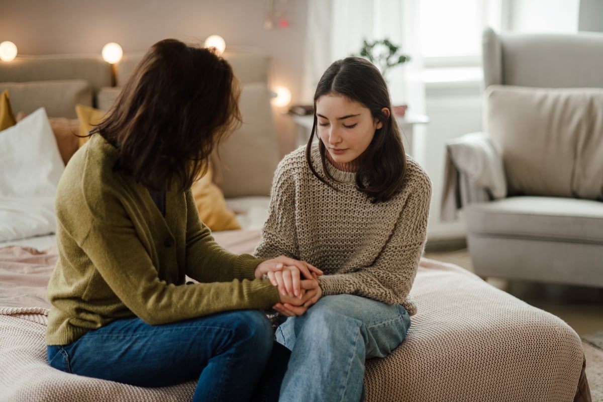 A teenage girl shares how her periods are going with her mother in a calm, supportive conversation at home
