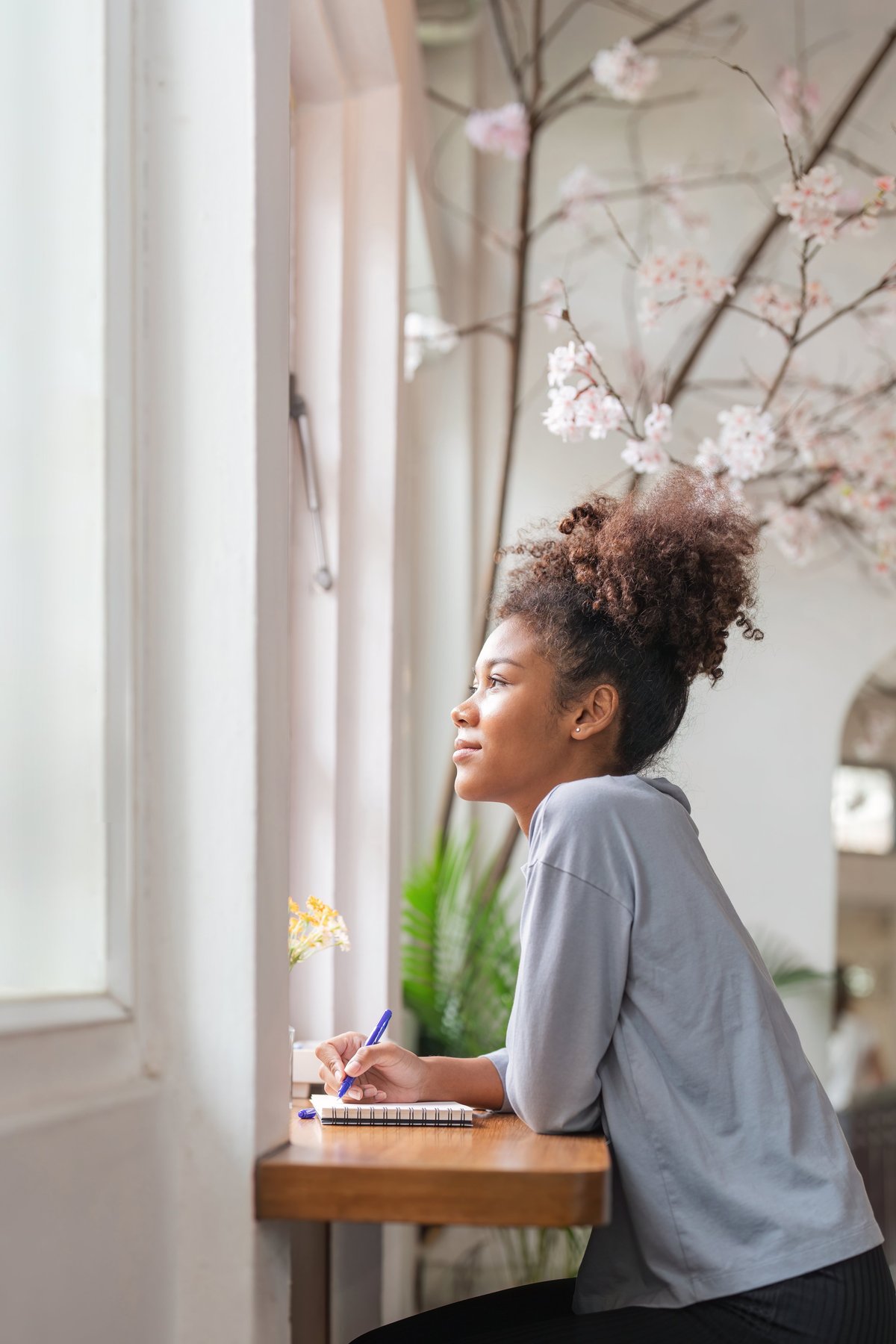 Woman journaling at home while learning about PCOS symptoms and the PMOS name change